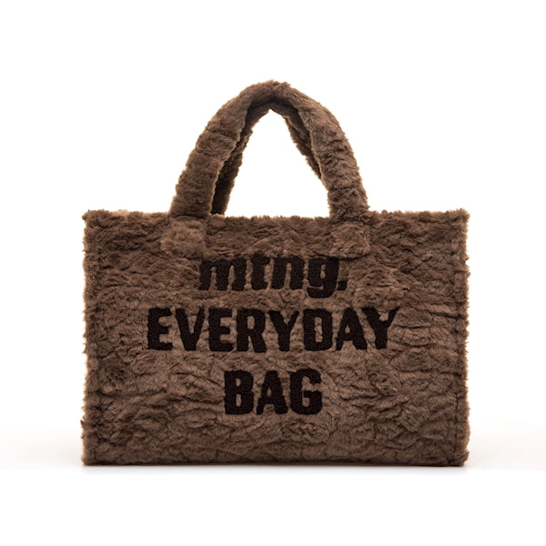 Mala Tote Mustang Fey castanho vista de frente, com a mensagem mtng. Everyday Bag em tom chocolate sobre acabamento em pelo suave, fundo branco
