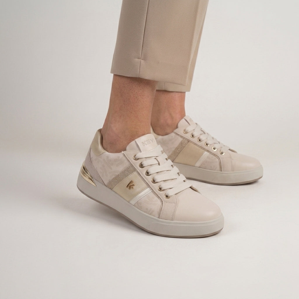 Pormenor dos pés calçados com as sapatilhas Keys 11870 Crema Cipria, com calças bege e fundo neutro.