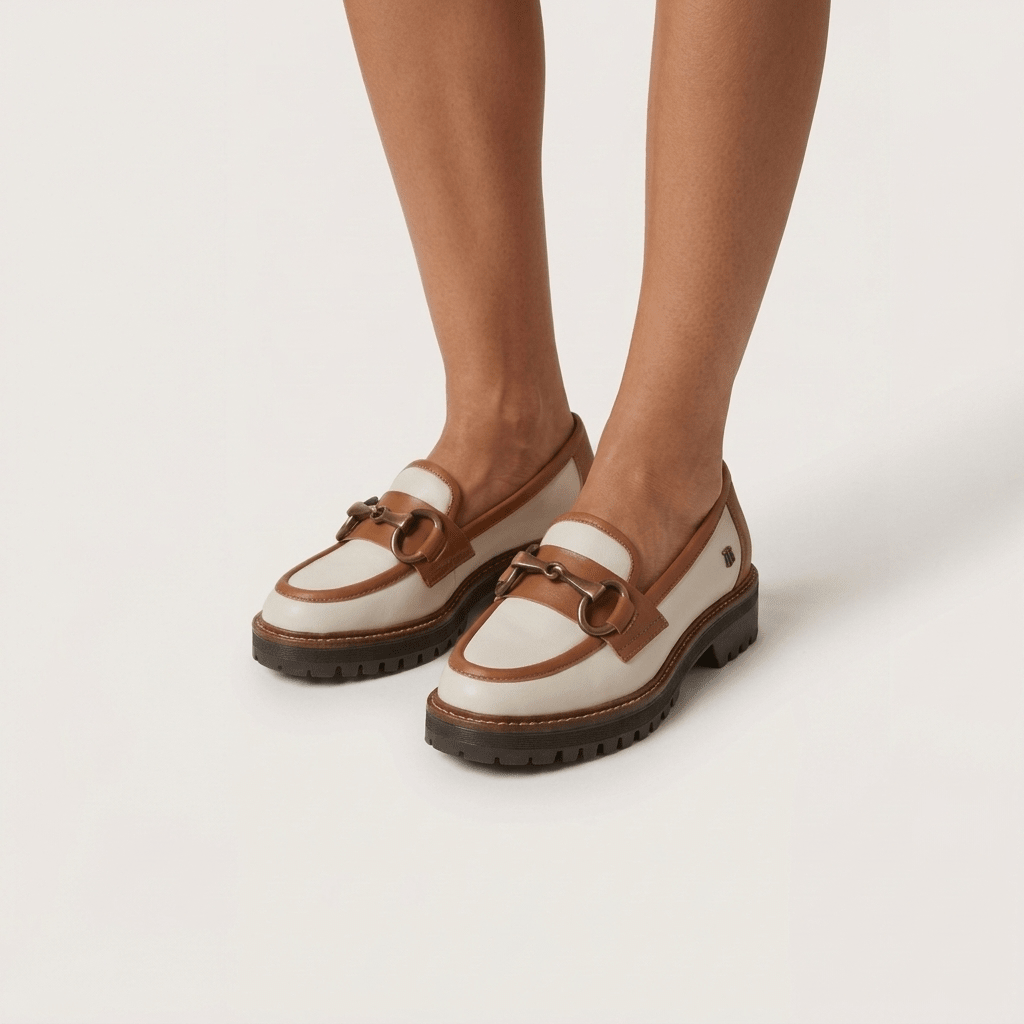Mocassim Feminino Ruika bicolor bege e camel calçado, pormenor dos pés e tornozelos, fundo branco neutro