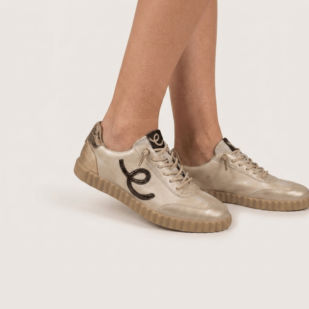 Sapatilhas femininas Elena Bloom em tom bege platino, com detalhes metalizados, vistas de lado numa modelo.