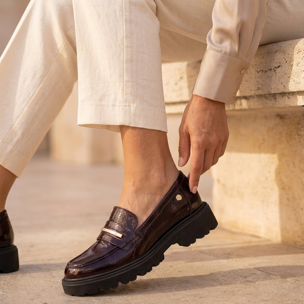 Detalhe do mocassim Carmela verniz bordeaux calçado, aplique metálico dourado na tira frontal