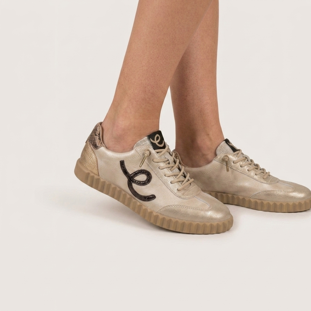 Sapatilhas femininas Elena Bloom em tom bege platino, com detalhes metalizados, vistas de lado numa modelo.
