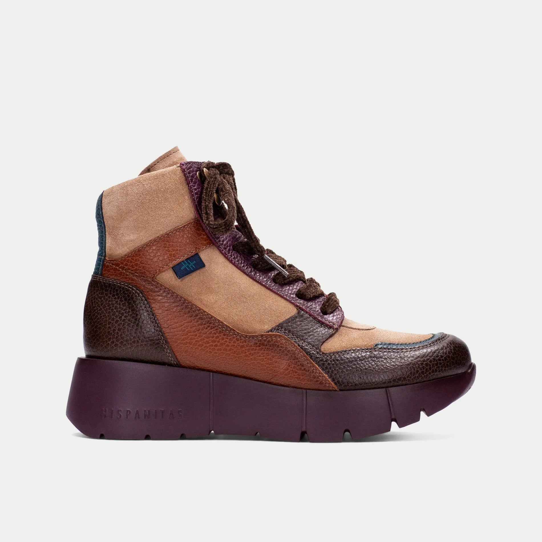 Botim Sport Hispanitas Chocolate-Amêndoa-Bordô visto de perfil lateral, em fundo neutro de estúdio, evidenciando o contraste entre camurça amêndoa, couro castanho e detalhes bordô, com sola grossa bordô e tecnologia Triflow.