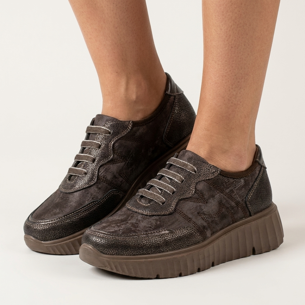 Pés de mulher com sapatilhas Mysoft Muse castanhas de plataforma sobre fundo cinzento claro