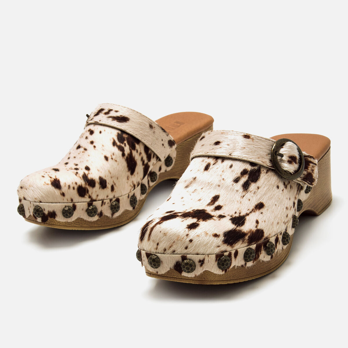 Pormenor da fivela redonda dourada e tachas laterais na sapatilha de salto alto Mustang Elois.