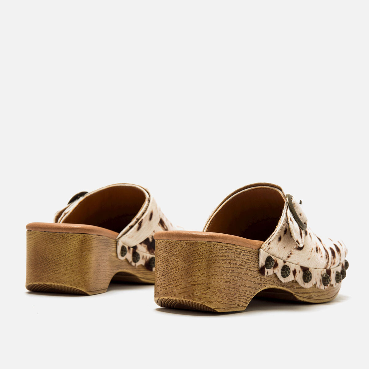 Vista lateral dos tamancos Mustang Elois com acabamento em pele sintética e detalhes de tachas laterais.