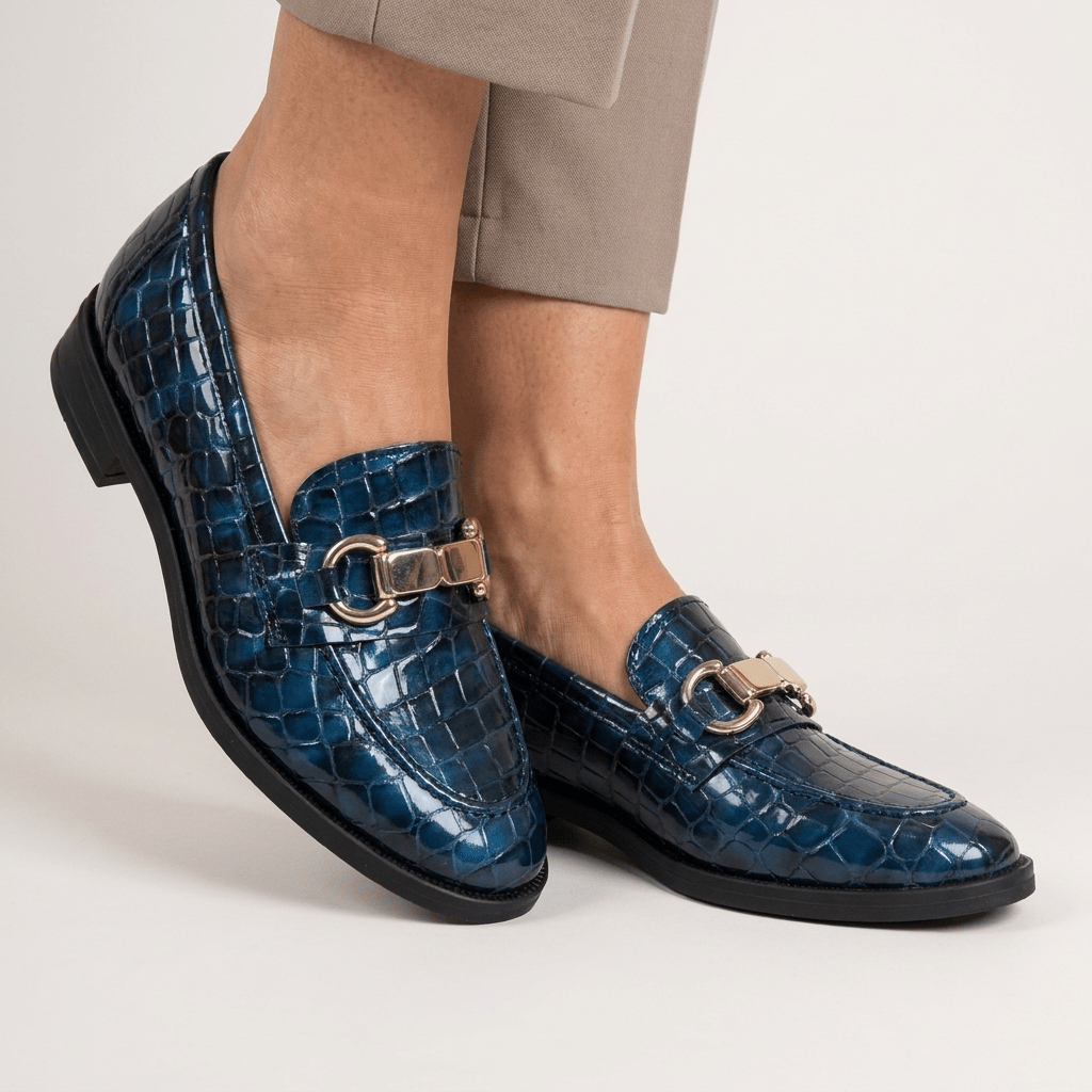 Mocassim Andrya azul oceano calçado, pormenor do efeito croco em verniz e do travessão dourado, fundo branco neutro