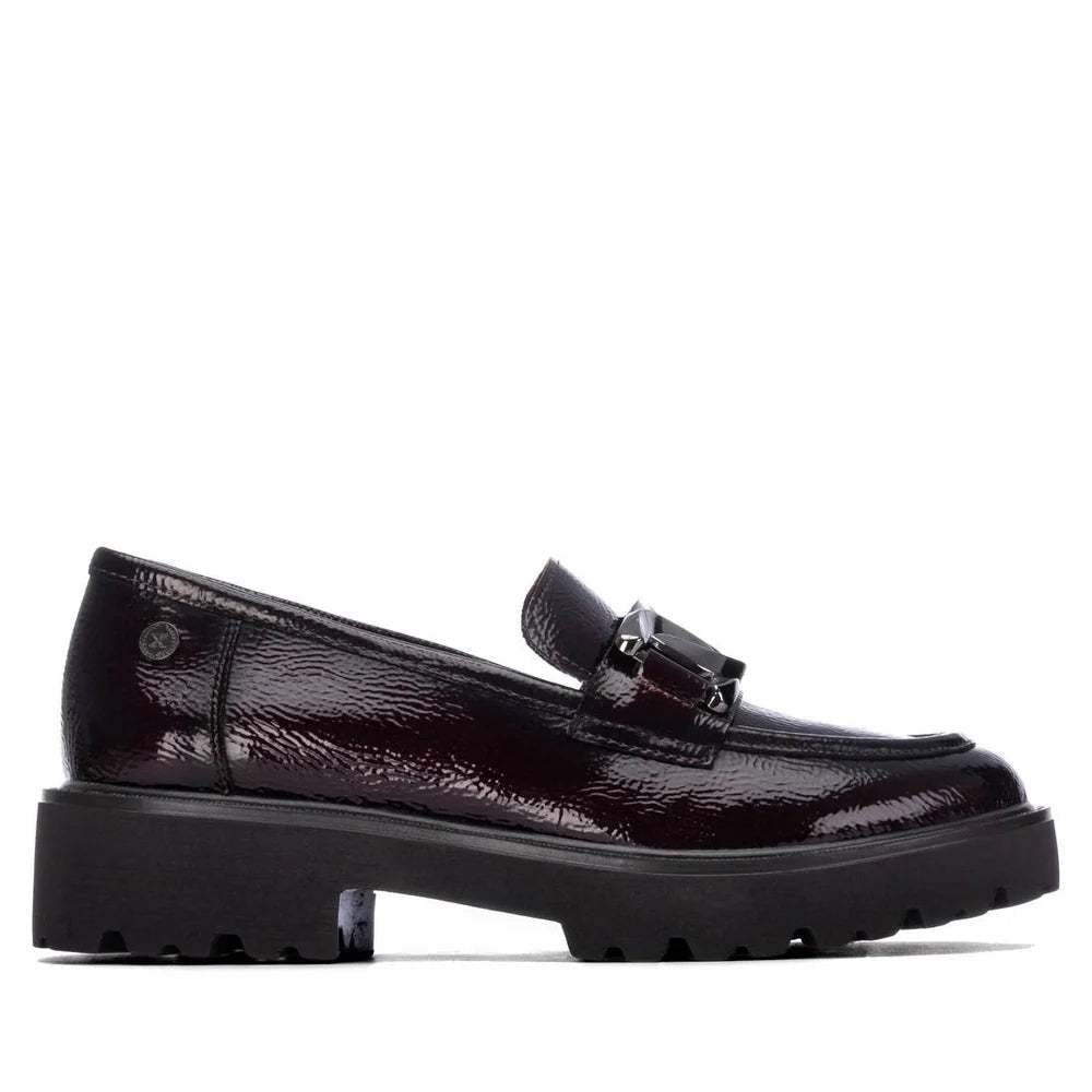 Mocassim XTI Bordeaux em pele envernizada, vista lateral completa, mostrando a fivela em corrente metálica e a sola grossa preta em estúdio.
