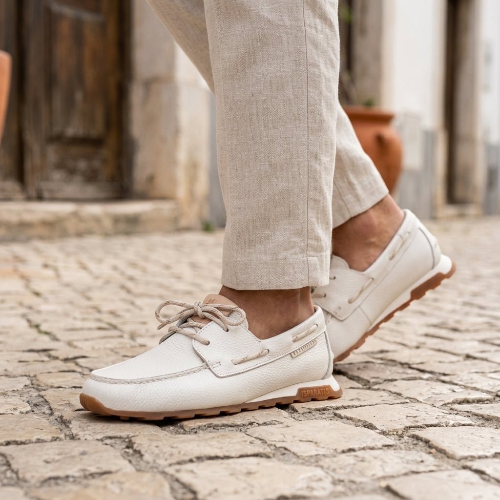 Pormenor do pé calçado com o Mocassim Hispanitas Zinnia branco, a caminhar numa rua de calçada portuguesa.
