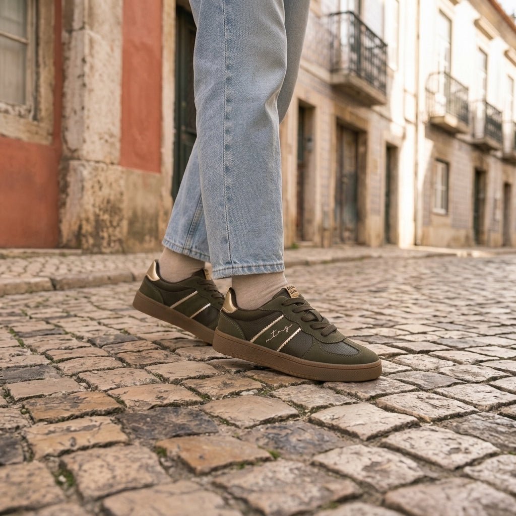 Ténis Mustang Roy caqui em movimento numa rua de calçada portuguesa, com detalhe metalizado dourado no contraforte — Roma Pell