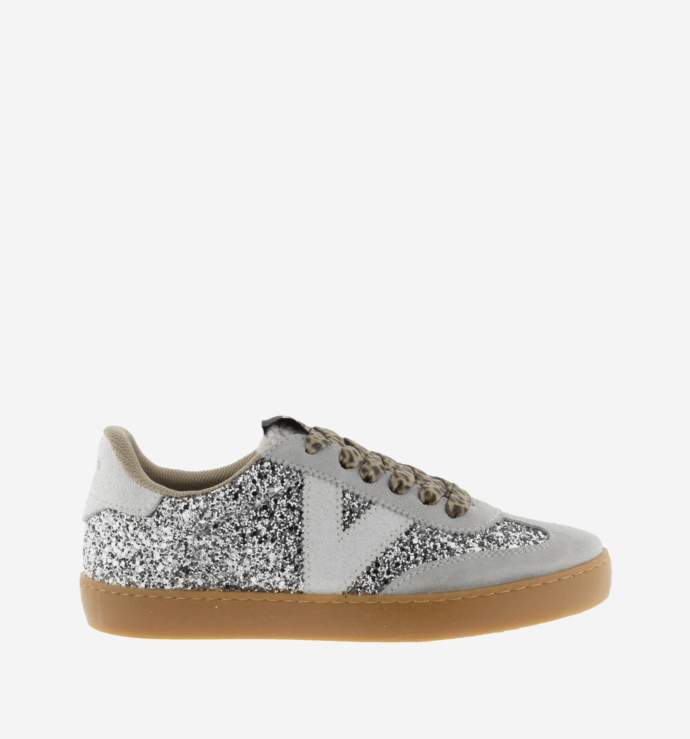 Ténis Victória em glitter prateado com painéis em camurça cinza-clara, atacadores animal print, logotípo V branco, sola caramelo, vista lateral