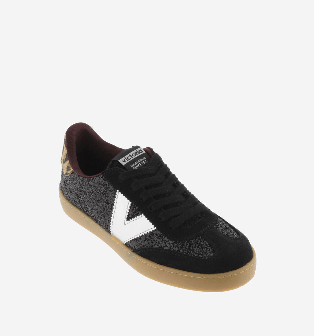 Ténis Victória glitter preto, vista frontal em ângulo elevado, contraforte em animal print, etiqueta Victoria visível na língua