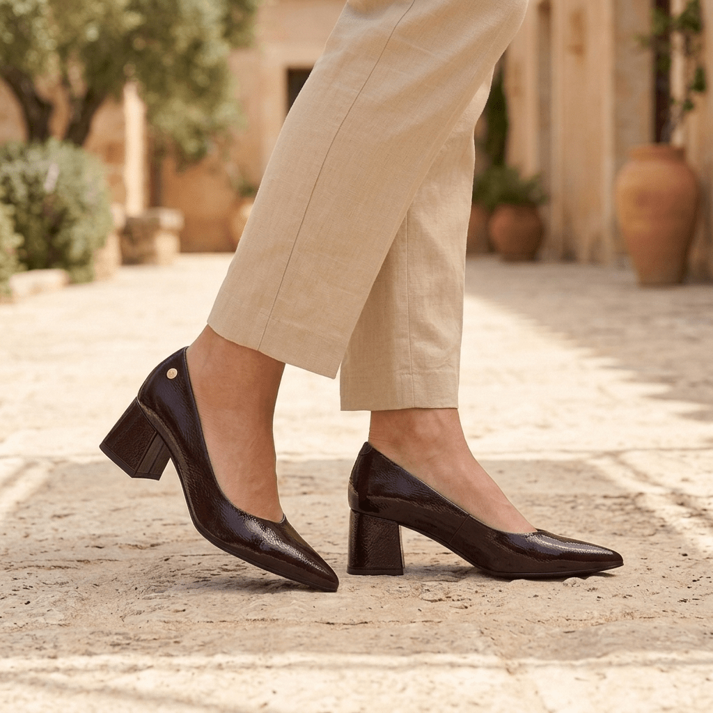 Pernas femininas em movimento sobre pátio de pedra, calças bege, calçando o par de Sapatos XTi Bordeaux.